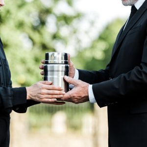 cropped view of senior man and woman holding mortuary urn